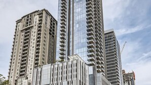 A high-rise building with a modern glass facade, surrounded by other tall buildings. - Luxury 1BR +Views+Rooftop Pool +Walk To Rainey St. (Austin)