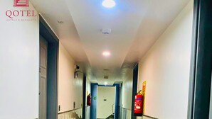 Pasillo de hotel con piso pulido, puertas a ambos lados y un extintor de incendios en la pared.