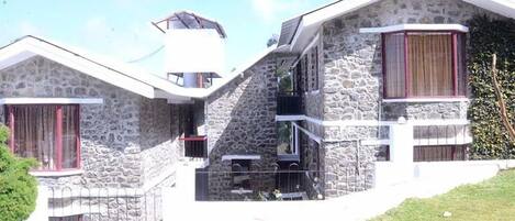 A stone building with a balcony and a small attached structure.