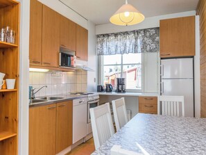 Cocina compacta con armarios de madera, un microondas, estufa y refrigerador.
