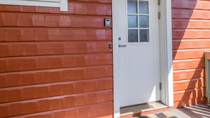 Une maison en bois rouge avec une porte blanche, une fenêtre et une boîte aux lettres.