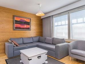 A modern living room with a grey sectional sofa, a white coffee table, and a grey armchair.
