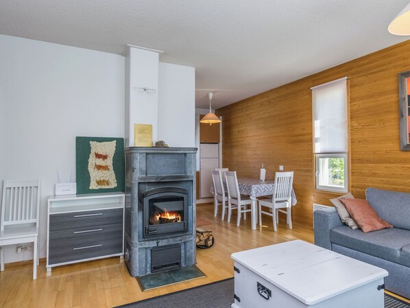 Una sala de estar acogedora con chimenea, paredes de madera, un comedor y un sofá.