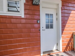 A white door with a glass panel, a mailbox, and a number '26' sign on a wooden wall.