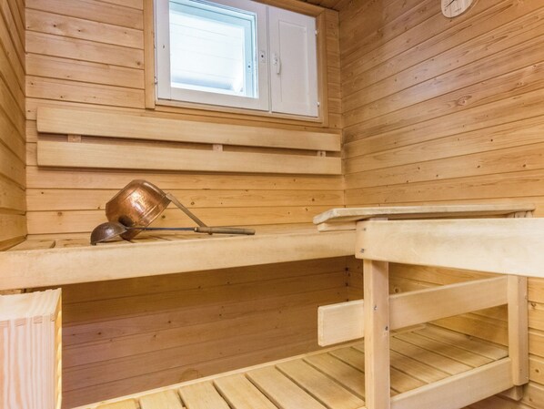 A wooden sauna with a bench, a small table, and a window.