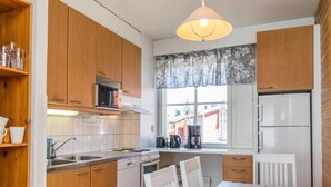 Une cuisine de taille réduite, dotée de meubles en bois, d’un four à micro-ondes, d’une cuisinière et d’un réfrigérateur.