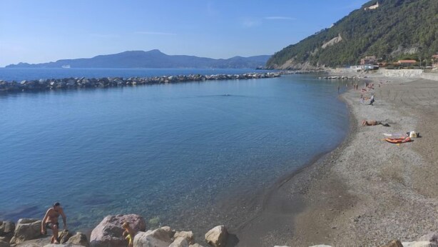 A beach with clear water, rocky shore, and a hilly backdrop. - Apartment Enrico by Interhome (Chiavari)