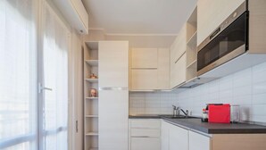 A modern kitchen with white cabinetry, a black microwave, and a red appliance on the counter. - Apartment Enrico by Interhome (Chiavari)