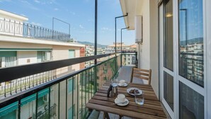 A balcony with a wooden table, chairs, and a view of the cityscape. - Apartment Enrico by Interhome (Chiavari)