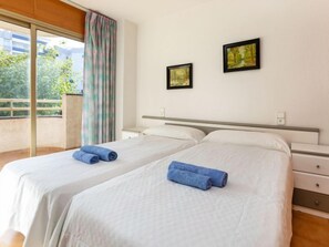 A hotel room with two beds, a balcony with a view, and two framed pictures on the wall.