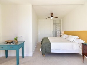 Un dormitorio con cama, escritorio, armario y ventilador de techo.