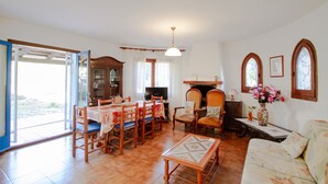 Ein geräumiges Wohnzimmer mit Essbereich, Kamin und großen Fenstern.