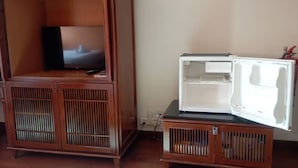 A compact living space with a wooden cabinet containing a television and a small refrigerator. - Alpine LXPD Premium Water Chalet (Port Dickson)