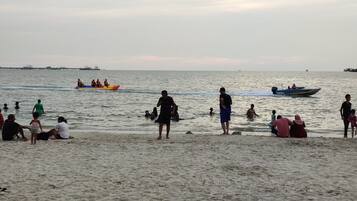 A beach with people swimming and boats in the water.
