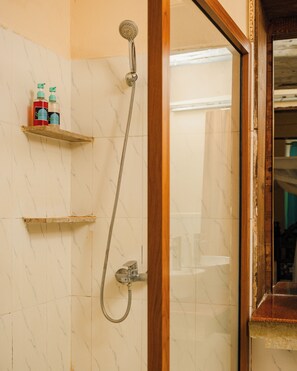 A bathroom with a shower, a wooden door frame, and a shelf with toiletries.