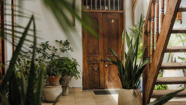 A wooden door with a number plate, potted plants, and a wooden staircase. - Emerald Palm Boutique Hotel (Zanzibar Town)