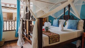 A bed with a canopy, a wooden headboard, and a patterned bedspread. - Emerald Palm Boutique Hotel (Zanzibar Town)