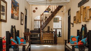 A traditional interior with wooden furniture, a staircase, and decorative items. - Emerald Palm Boutique Hotel (Zanzibar Town)