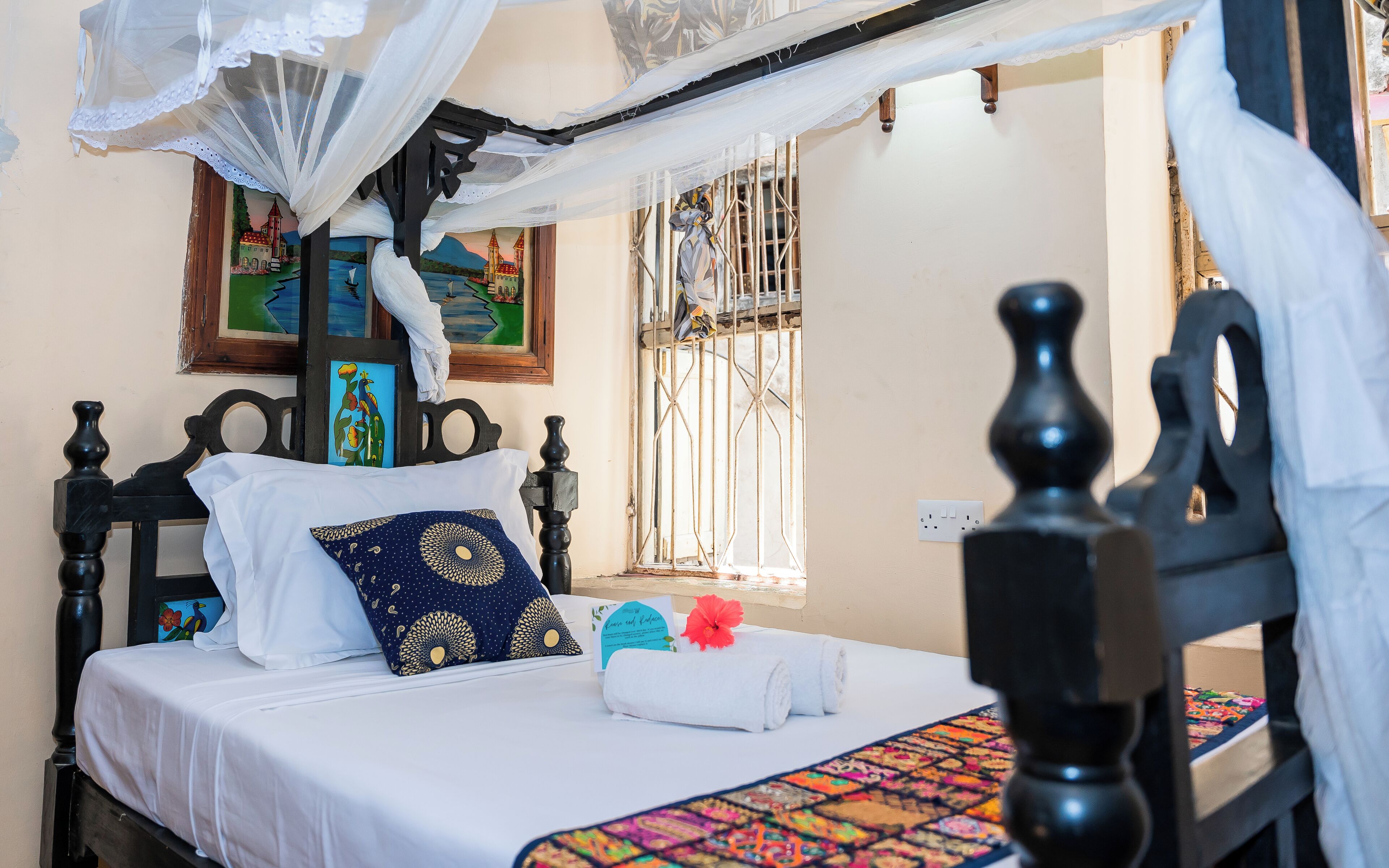 A bed with a white bedspread, a blue patterned pillow, and a decorative headboard.