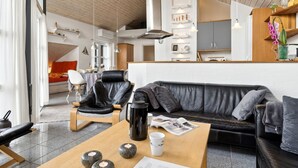 Ein modernes Wohnzimmer mit einer schwarzen Ledersofa, einem Couchtisch aus Holz mit dekorativen Steinen und einem schwarzen Sessel.
