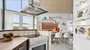Eine moderne Küche mit Einbauofen, Edelstahl-Dunstabzugshaube und Essbereich mit Holztisch und Stühlen.