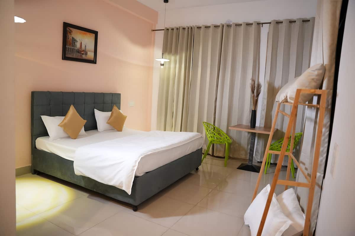 Um quarto com cama, cadeira, escada e cortina.