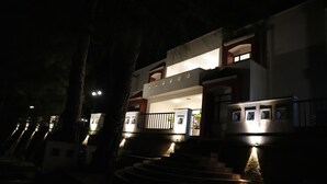 Maquete de um edifício moderno com escada que leva a uma varanda, iluminada por luz artificial.