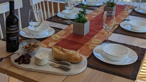 Une table à manger dressée avec des assiettes, des verres et une bouteille de vin, donnant sur un paysage arboré.