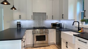 A modern kitchen with white cabinets, a stainless steel stove, and black countertops. - Downtown Picton, 3 bedroom. (Prince Edward)