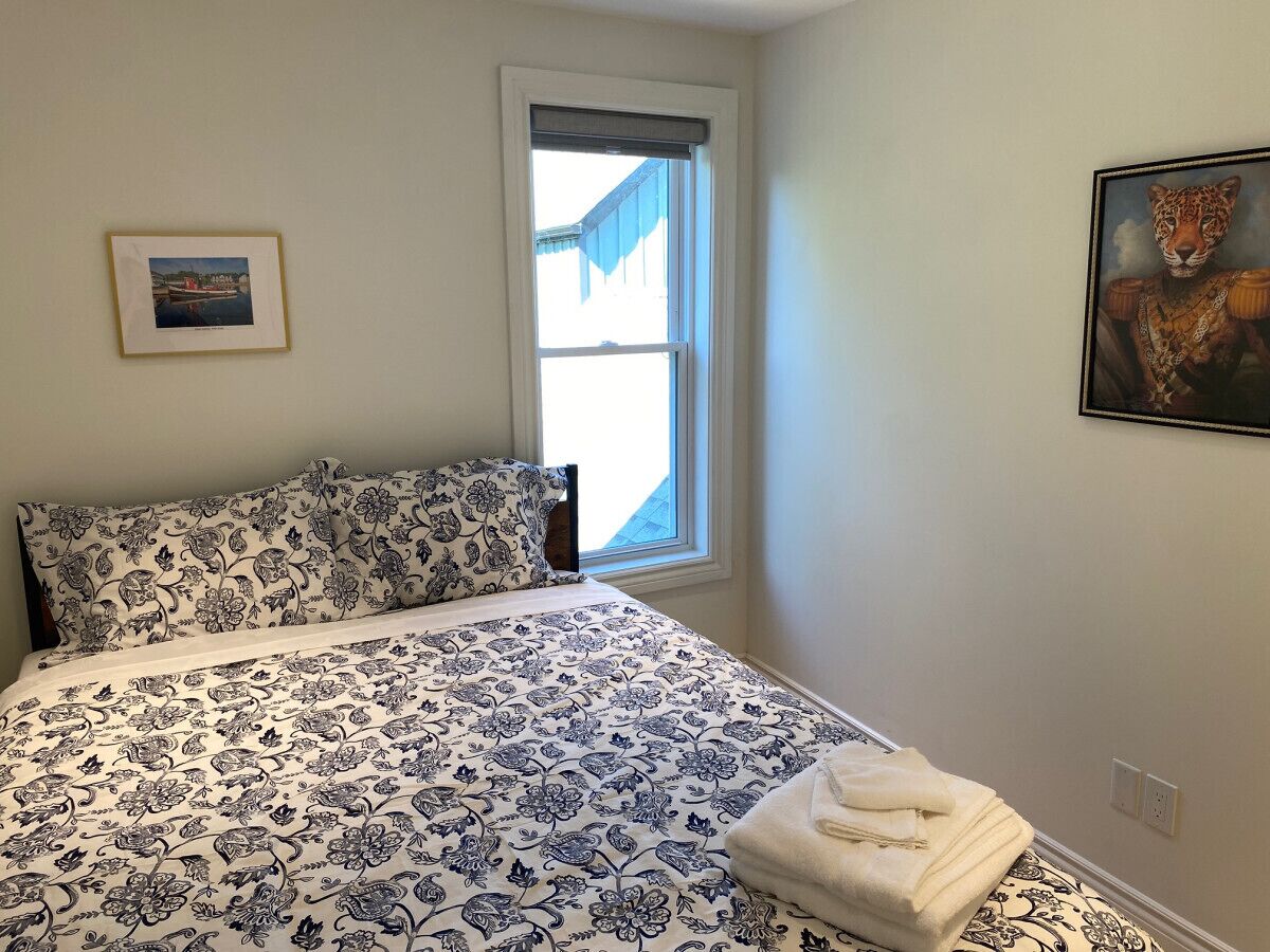 Una camera da letto con un letto, una finestra, un quadro e una foto incorniciata al muro.