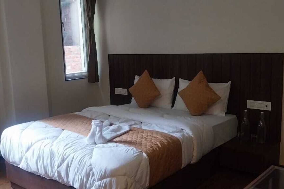 Cama bem arrumada com cabeceira de madeira, dois travesseiros e um edredom.
