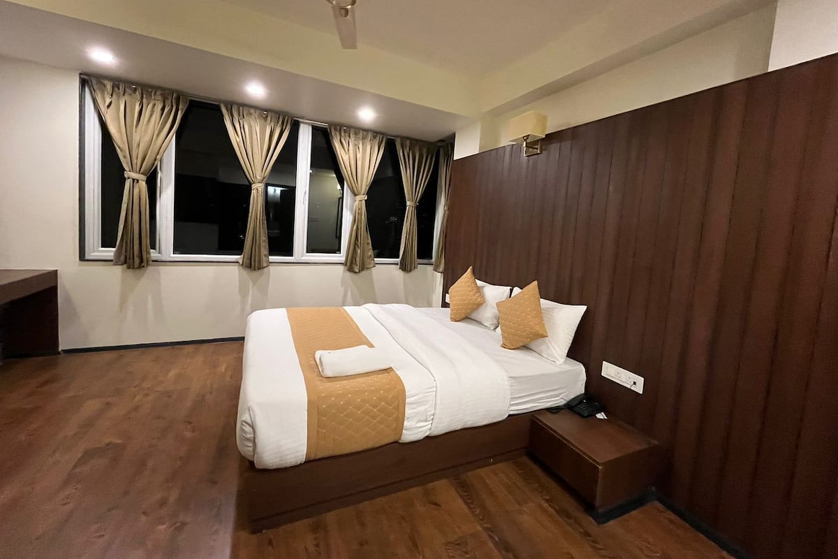 Quarto moderno com cama grande, cabeceira de madeira e ventilador de teto.