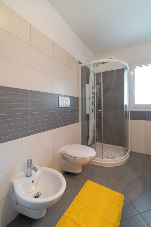 Un baño moderno con cabina de ducha, un bidé y un inodoro.