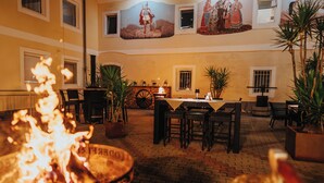 A courtyard with a fire pit, outdoor seating, and a mural on the wall. - Hotel Leo (Steyr)