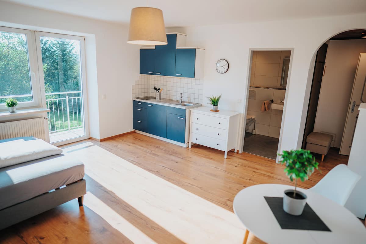 A modern kitchen with blue cabinets, a white countertop, and a wooden floor.