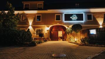 A hotel entrance with a sign reading "S'LEO HOTEL" and a brick pathway leading to the door.