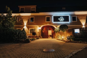 A hotel entrance with a sign reading "S'LEO HOTEL" and a brick pathway leading to the door.