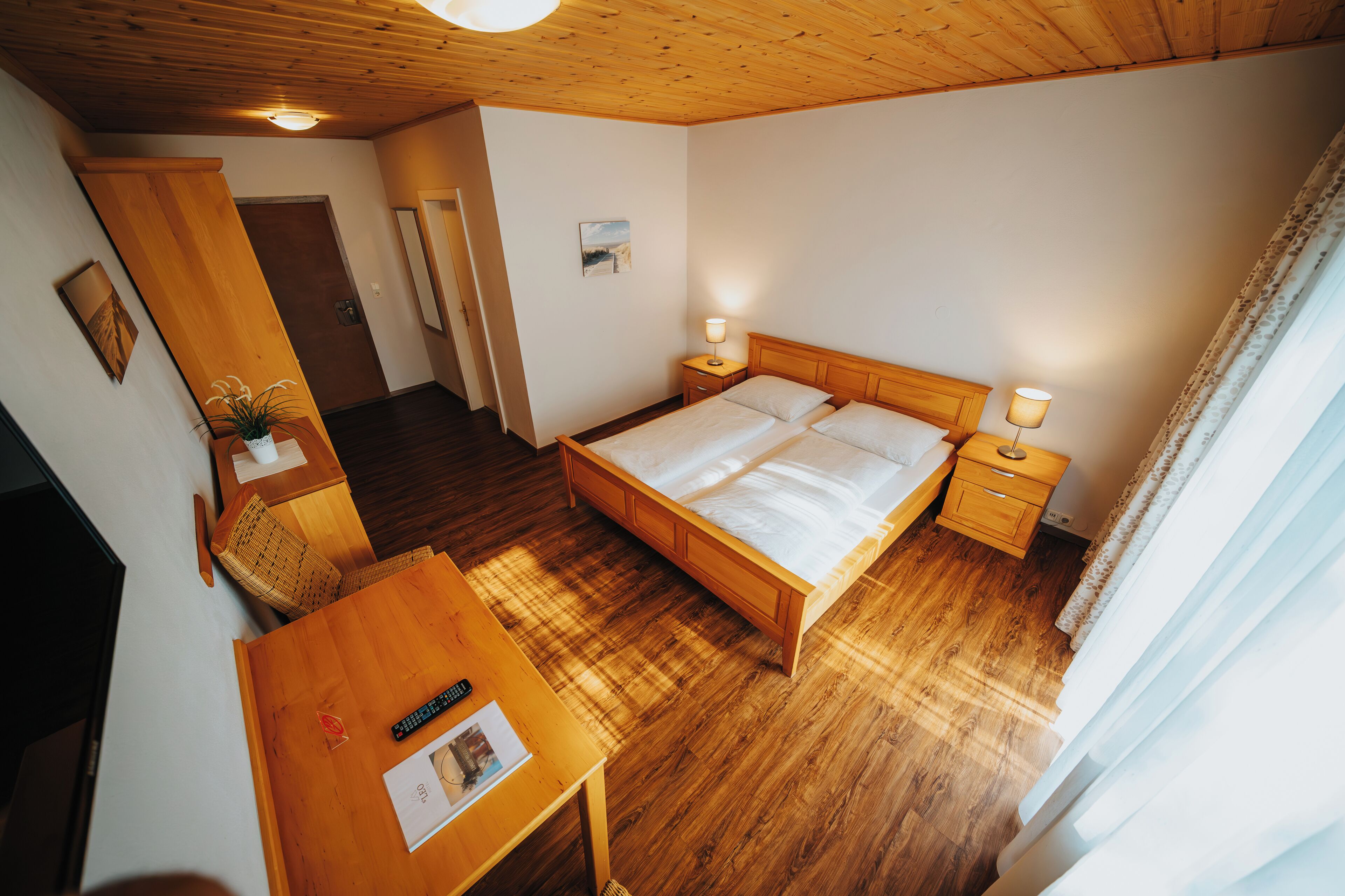 Ein Schlafzimmer mit einem hölzernen Bett, Nachttischen, einem Schreibtisch und einem Stuhl.