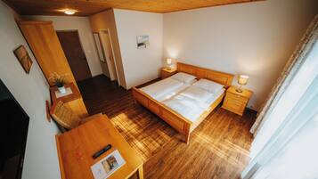 Ein Schlafzimmer mit einem hölzernen Bett, Nachttischen, einem Schreibtisch und einem Stuhl.