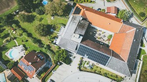 An aerial view of a residential property with a swimming pool, solar panels, and a well-maintained garden. - Hotel Leo (Steyr)