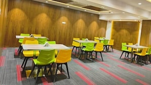A conference room with multiple tables and chairs, wooden panel walls, and recessed ceiling lighting.