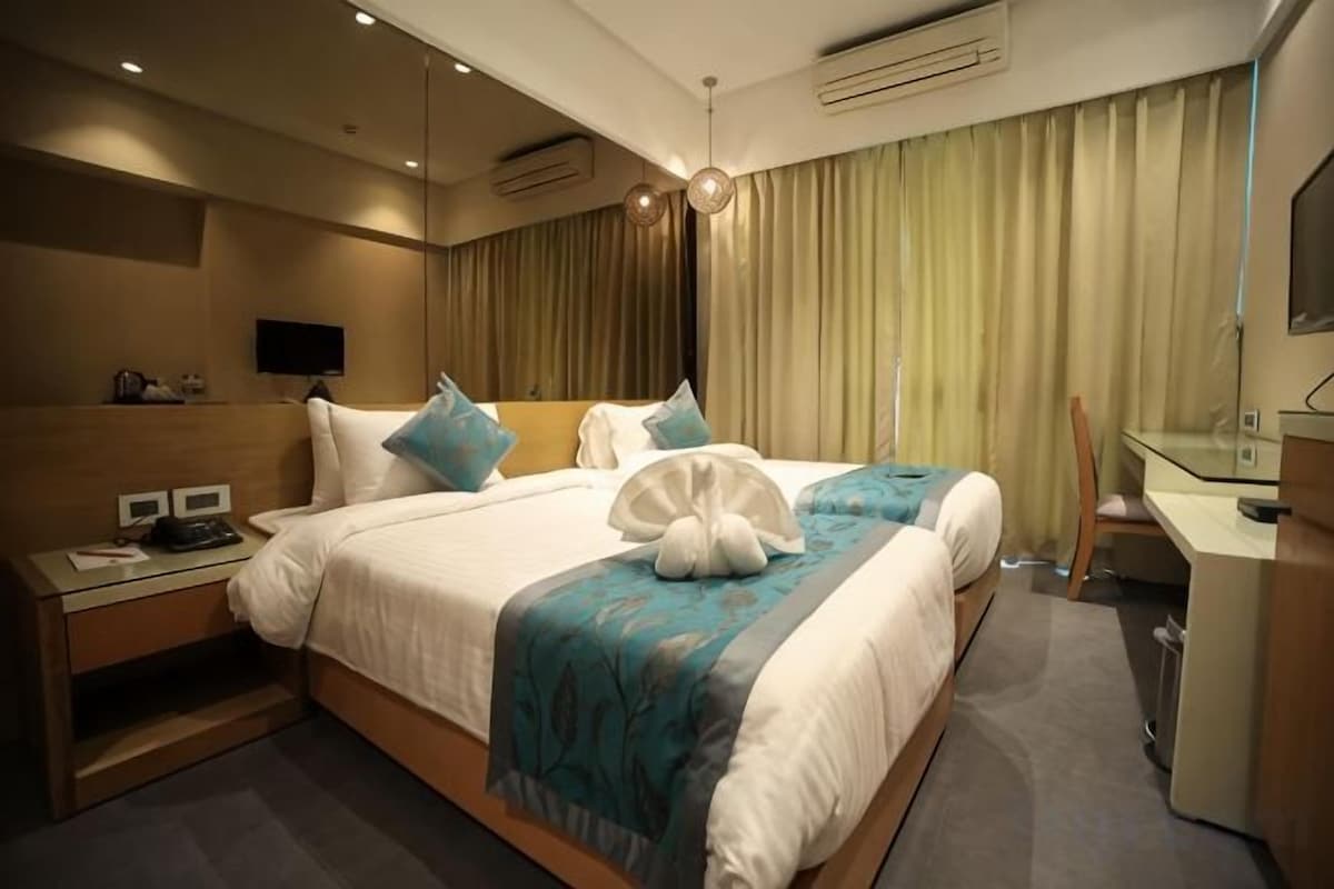 A hotel room with a large bed, bedside tables, a desk, and a television.