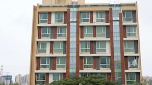A multi-story building with a symmetrical facade, large windows, and a central vertical feature.