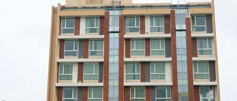 A multi-story building with a symmetrical facade, large windows, and a central vertical feature.