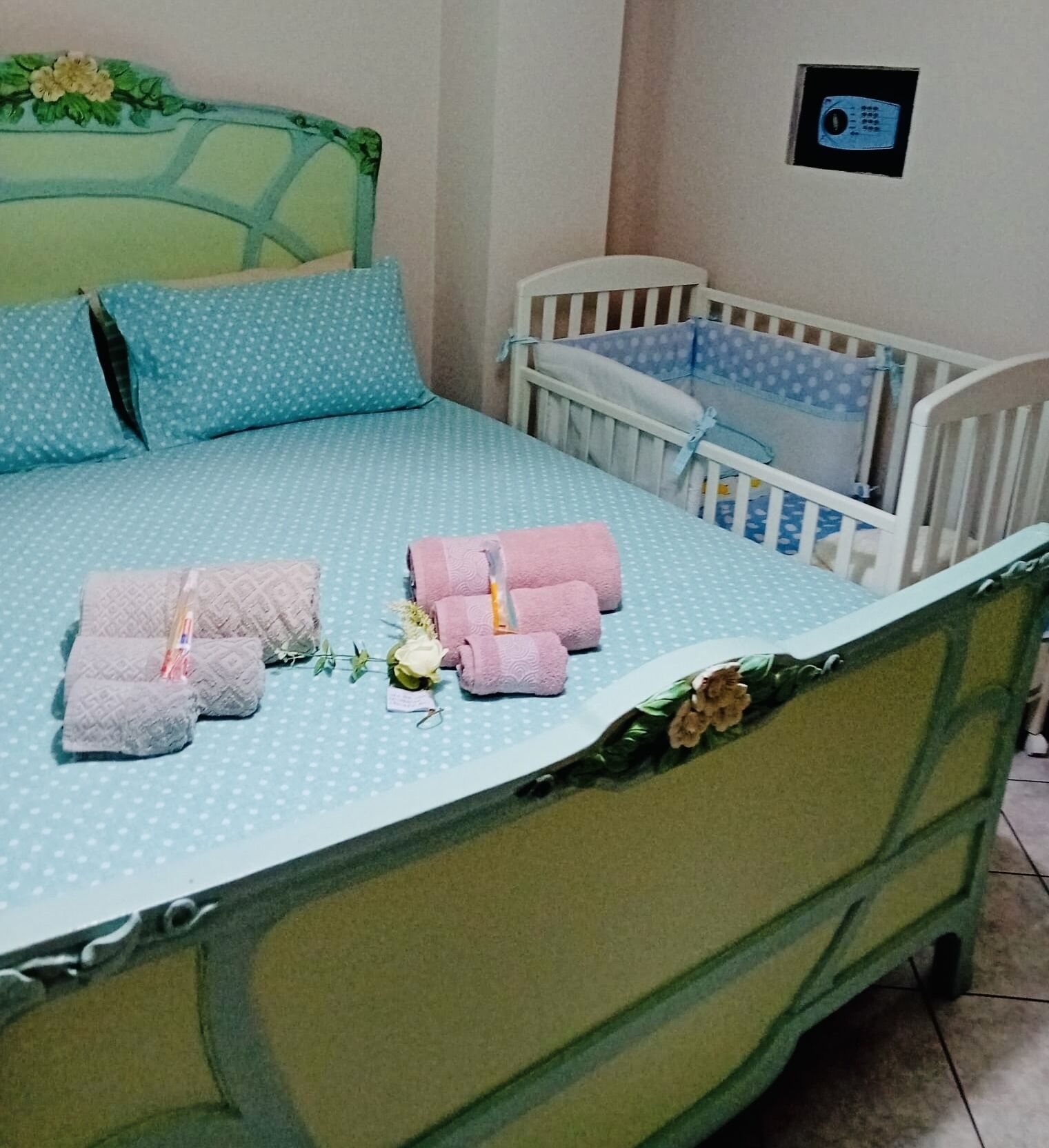 Un lit bien fait, avec une couvre-lit à pois bleus, deux oreillers et des serviettes roses.