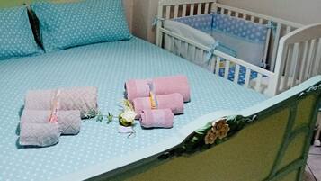 Un lit bien fait, avec une couvre-lit à pois bleus, deux oreillers et des serviettes roses.