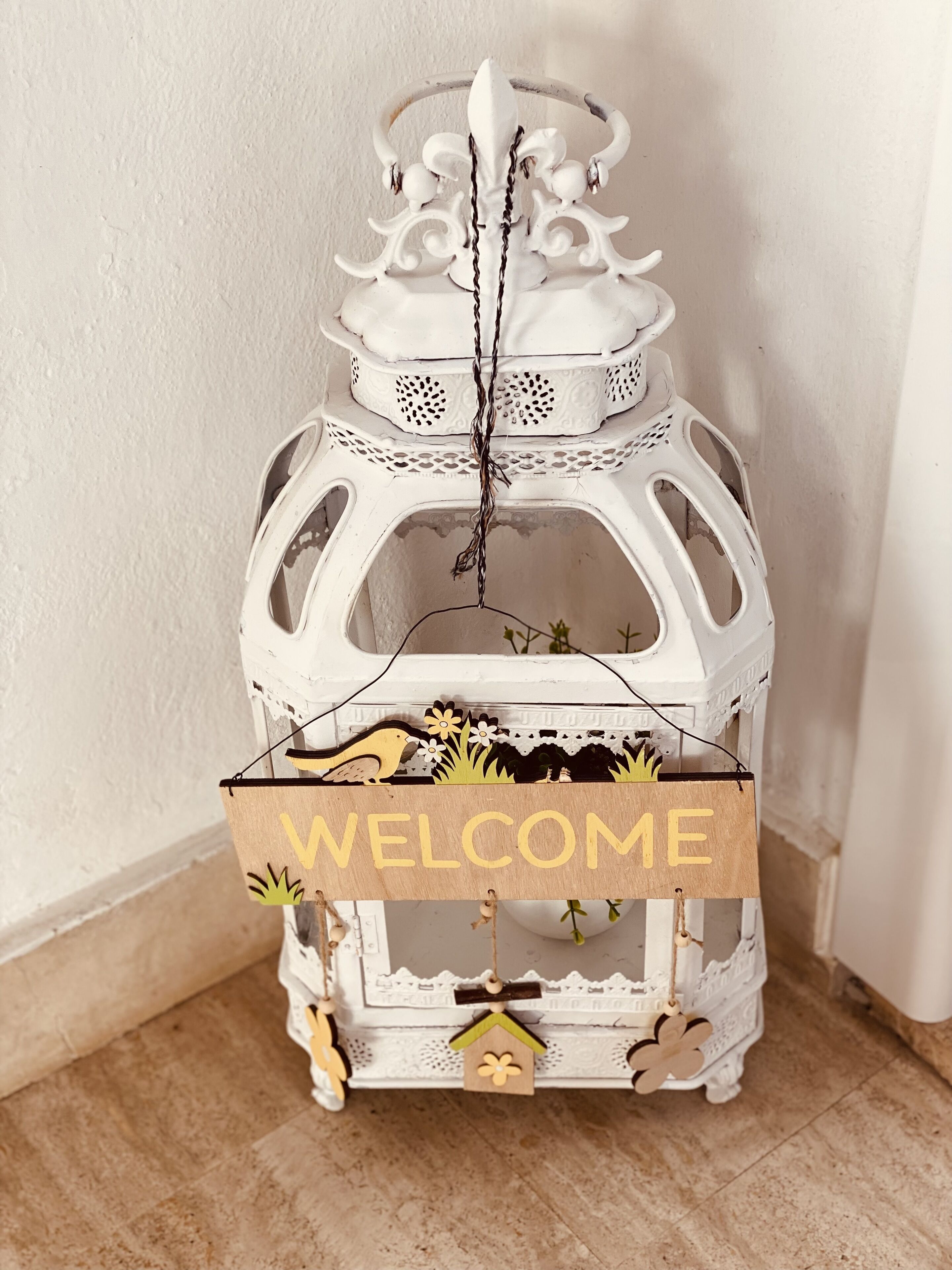 Un farol decorativo blanco con un cartel que dice 'WELCOME' colgado.