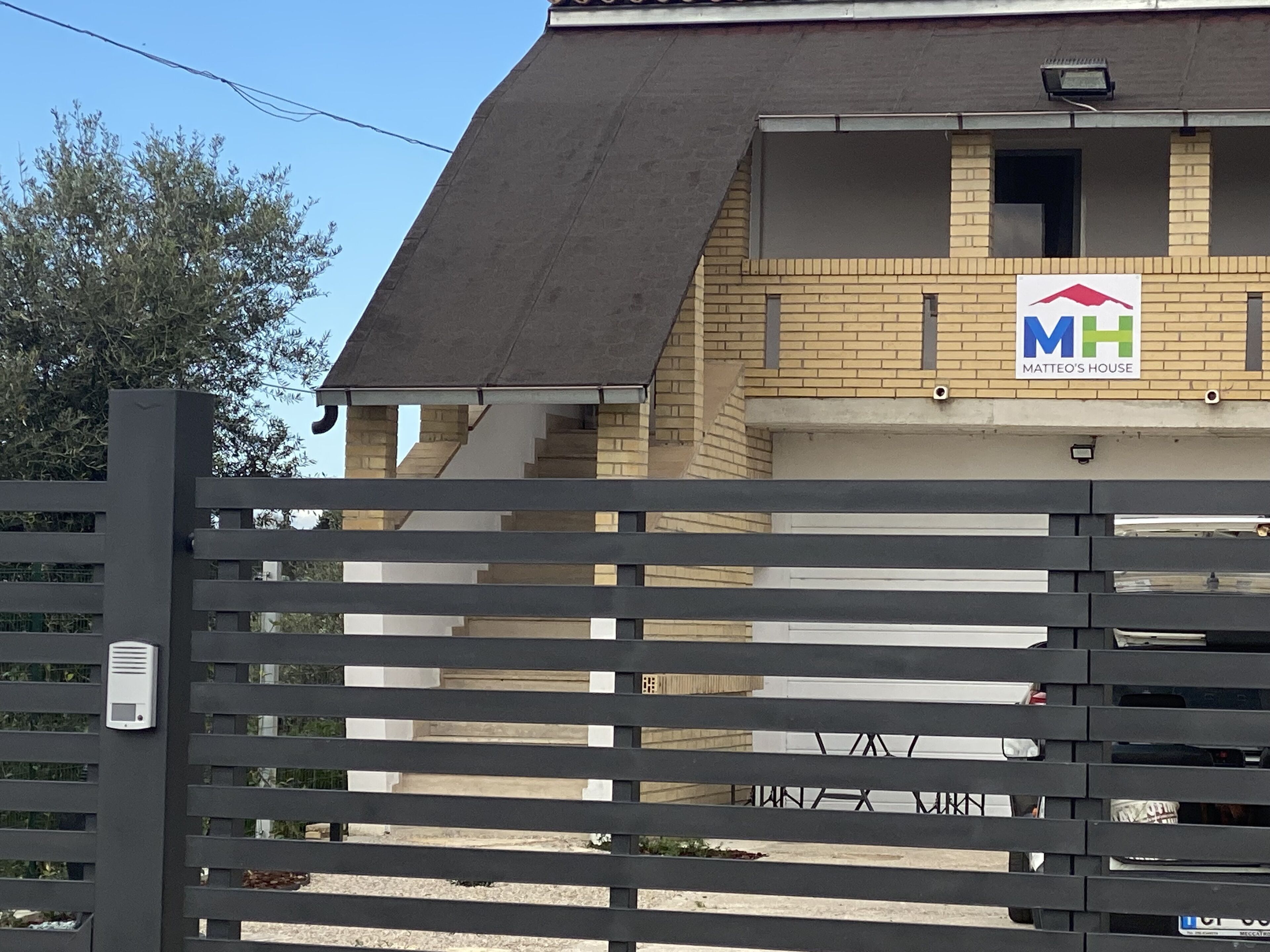 A building with a sign reading "Matteo's House" and a gated entrance.