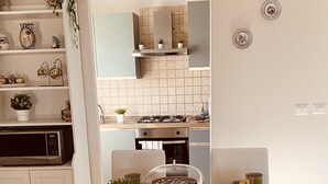 Een eettafel gedekt met borden, glazen en een taartplateau in een moderne keuken met witte kasten en een betegelde achterwand.