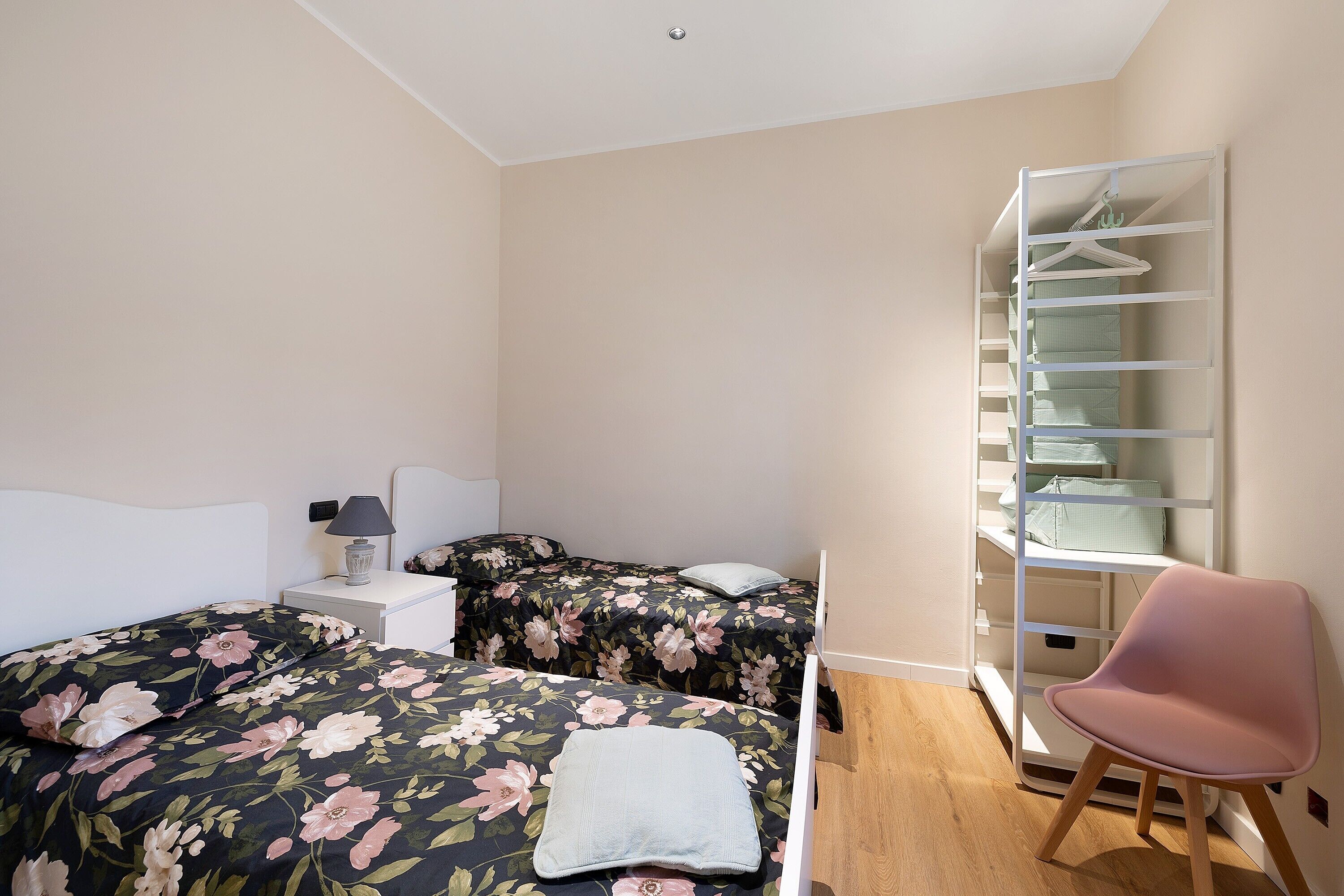 Une chambre avec deux lits, une table de chevet avec une lampe, une chaise et une armoire.